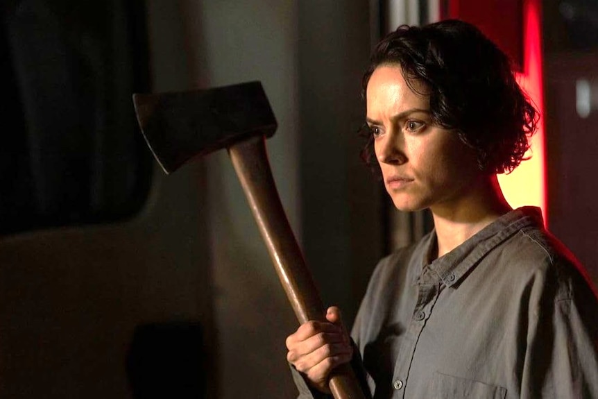 A woman holds an axe.