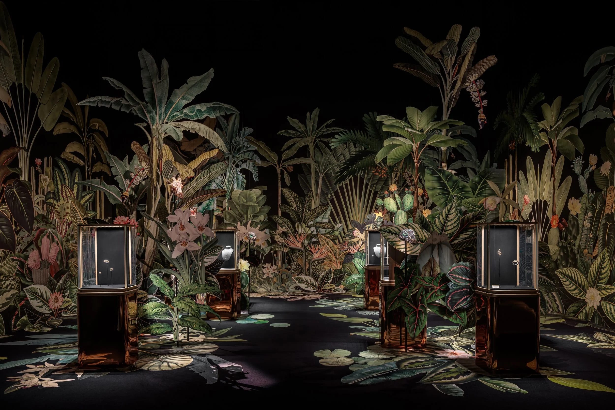 A colorful retail installation for Cartier by Clare Celeste of foliage against a black background, interspersed with cases of jewelry