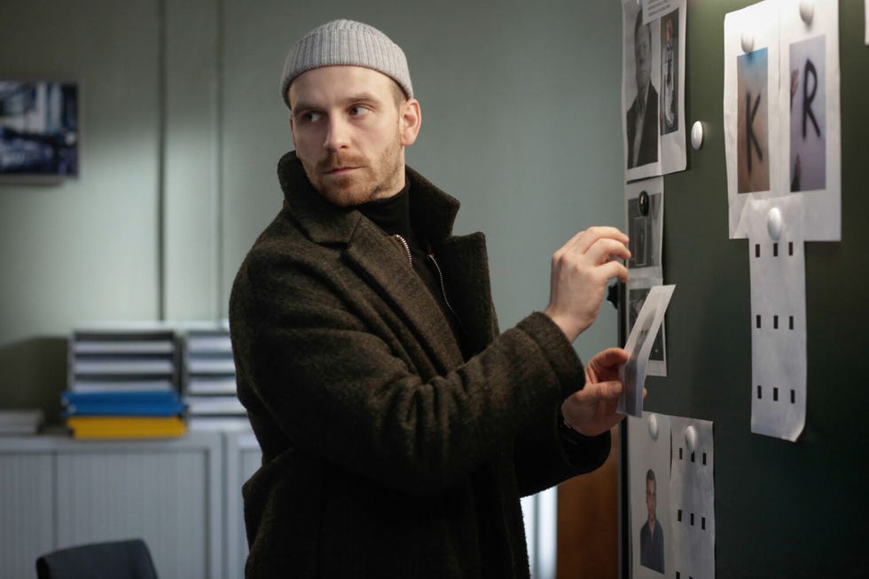 person interacting with a bulletin board displaying photographs and notes
