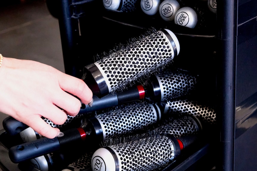 Hands handle hairdressing equipment.