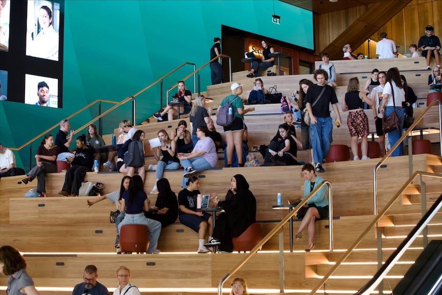 A multi-storey mustard coloured building with decking and grass surrounding it