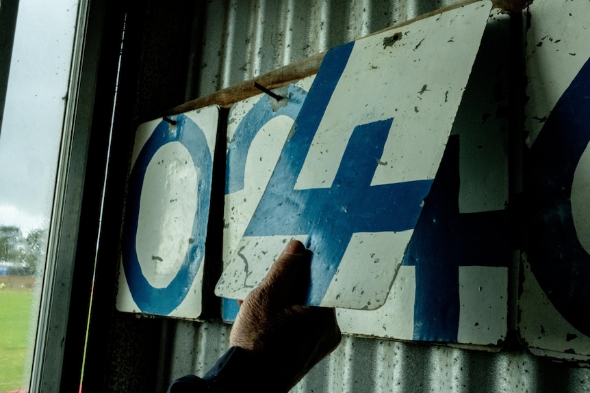 A hand turning a old fashioned scoreboard.