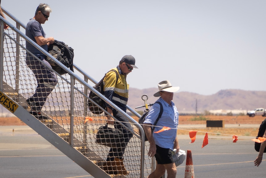 People walk off a plane in fluorescent work clothes