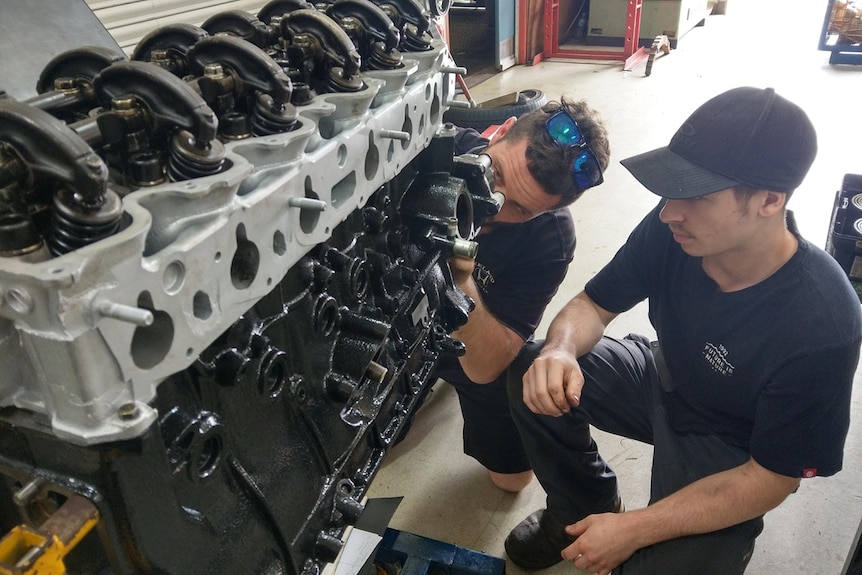 two people working on an engine
