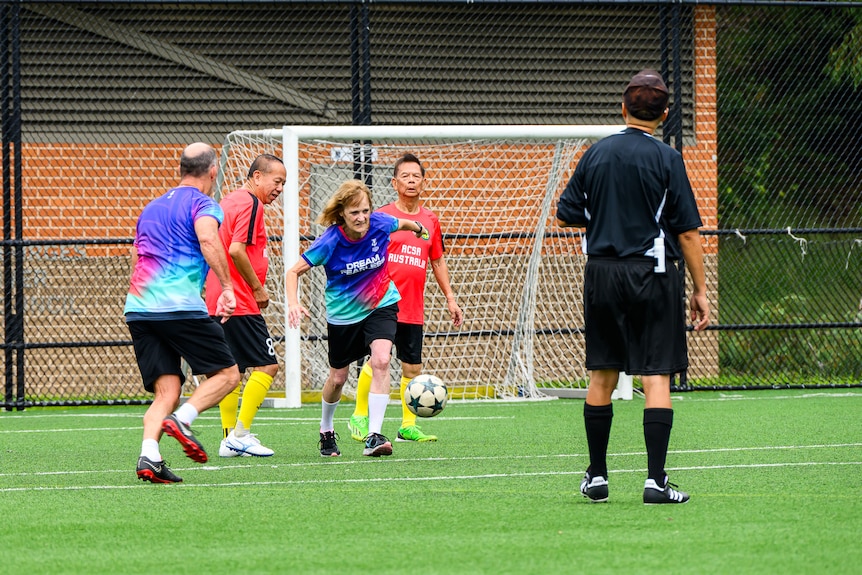 An older woman runs with a football during a game.