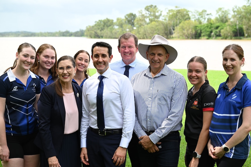 A group of people pose for a photograph on a riverbank.