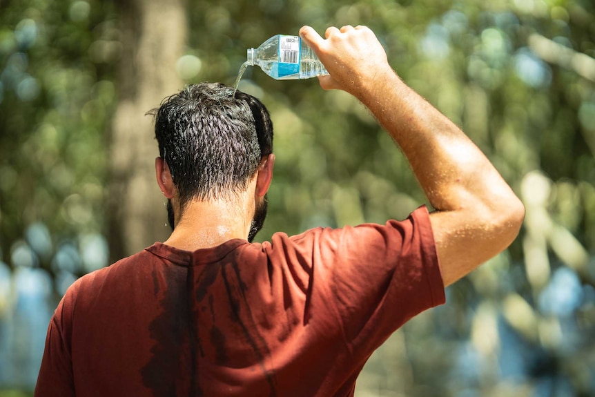 A man pouring water on himself during a run in hot weather.
