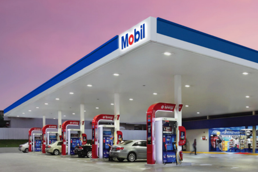 A Mobil petrol station at sunset with cars parked at bowsers
