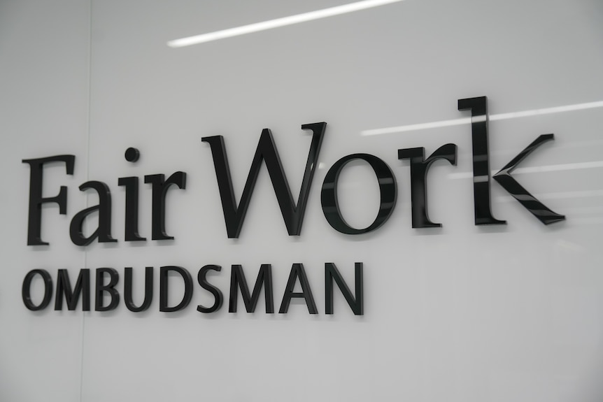 A sign on a white wall that says 'Fair Work Ombudsman'.