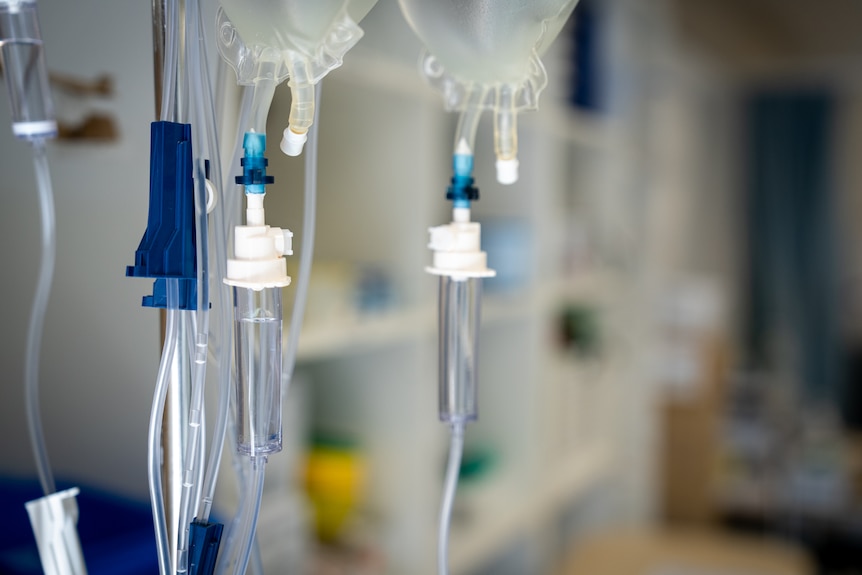 Bags of intravenous fluids hooked up to tubes in a hospital room