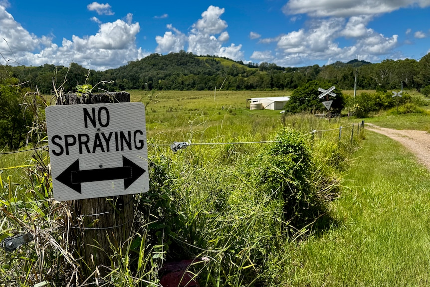 A sign on a country fence post that says no spraying.