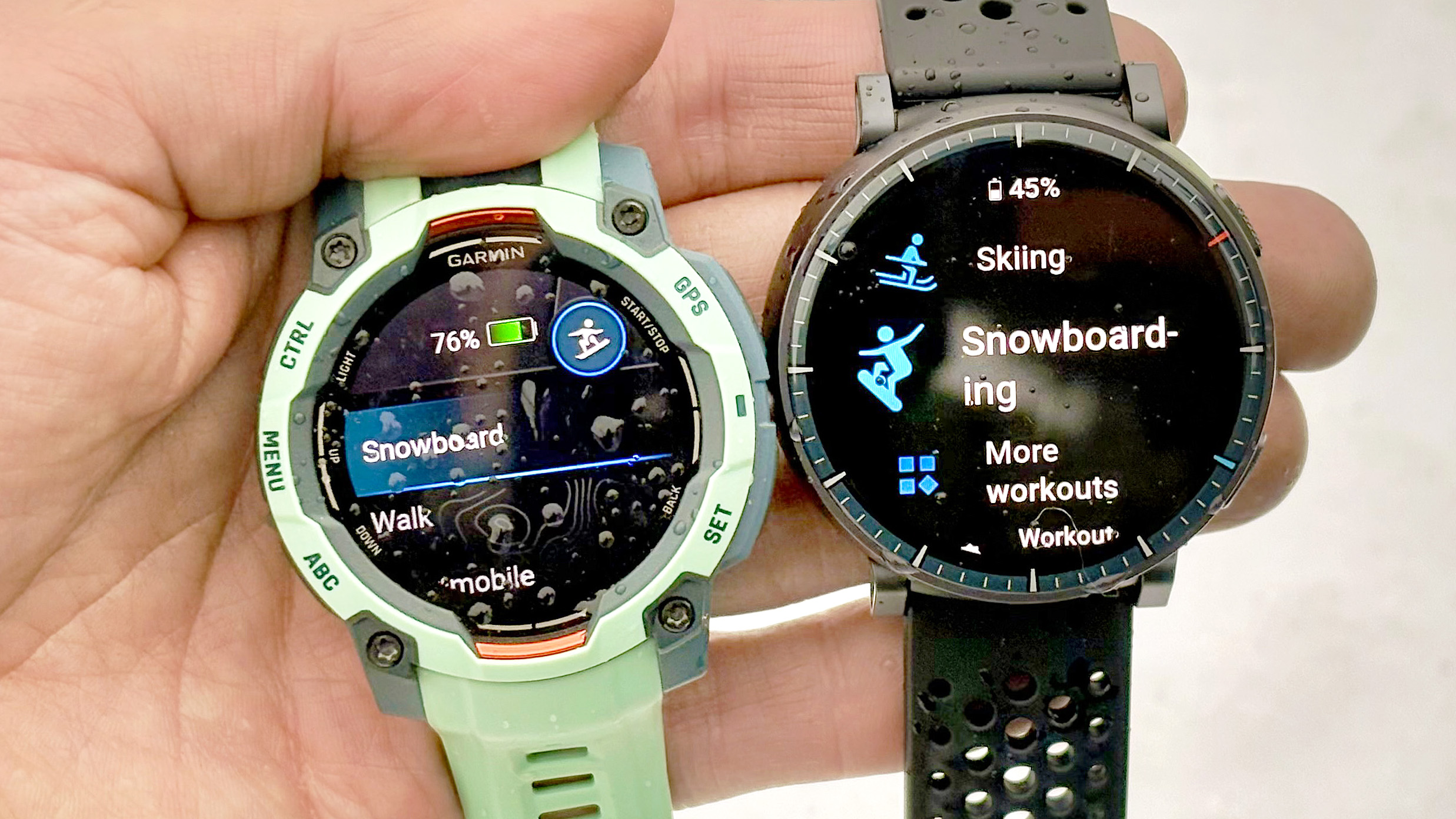 Close-up of the Garmin Instinct 3 and Amazfit Active Max in a user's hand with snow in the background