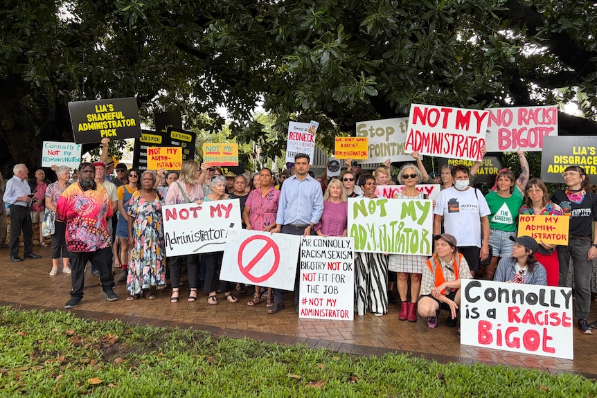 About 100 people stand in a group holding signs which do not support NT Administrator David Connolly.