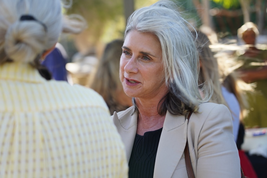 A female politician speaking to another woman at a memorial service.   