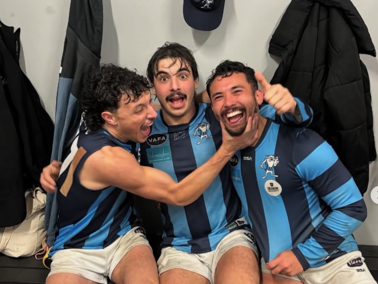 Three AFL players hugging and laughing