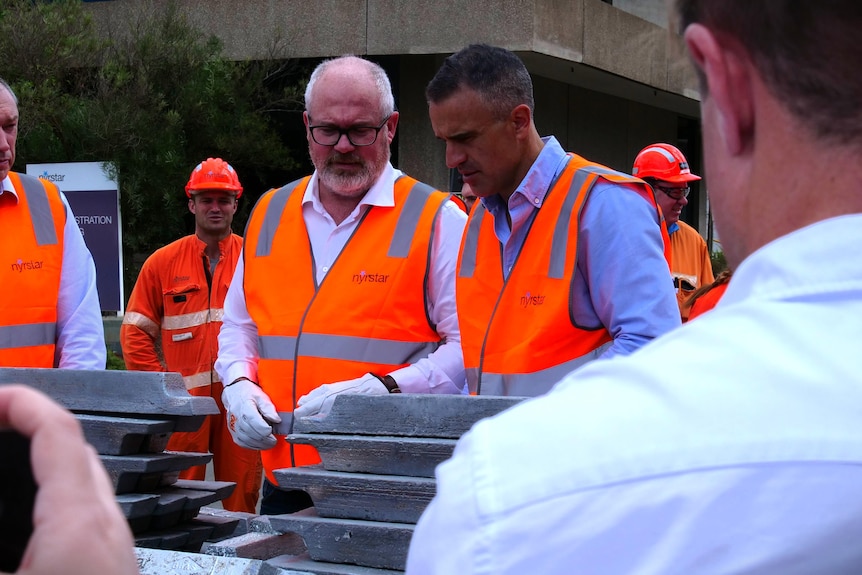 Peter Malinauskas in high-vis holding critical mineral antimony in Port Pirie