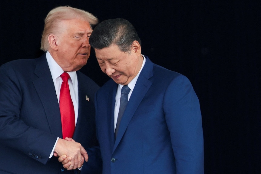 Donald Trump and Xi Jinping talk as they stand together.