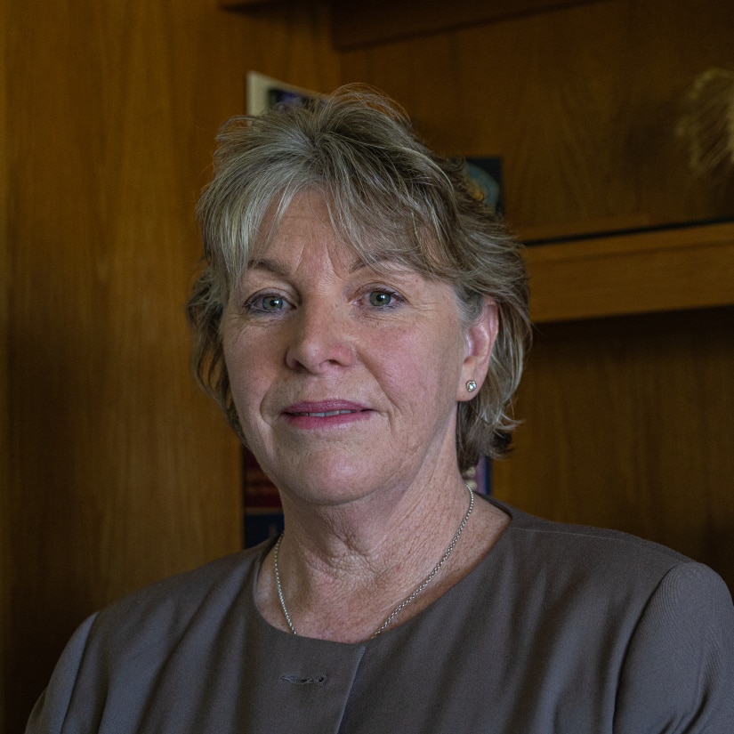A profile image of a middle-aged woman in front of a shelving unit
