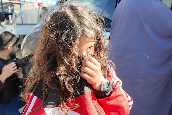An Australian child shields their face as the group prepared to leave the al-Roj camp last Monday.