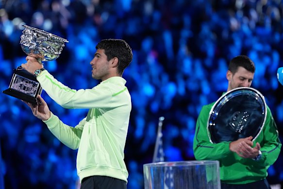 Alcaraz holds the spoils of victory aloft while Djokovic gets acquainted with the runners-up silverware for the first time at the AO.