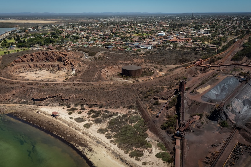 Drone shot of a steel factory next to land dug out at a mining site next to a town