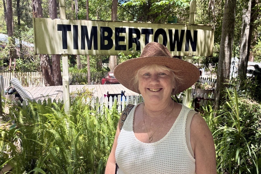 A woman with a wide-brimmed hat smiles looking towards the camera. 