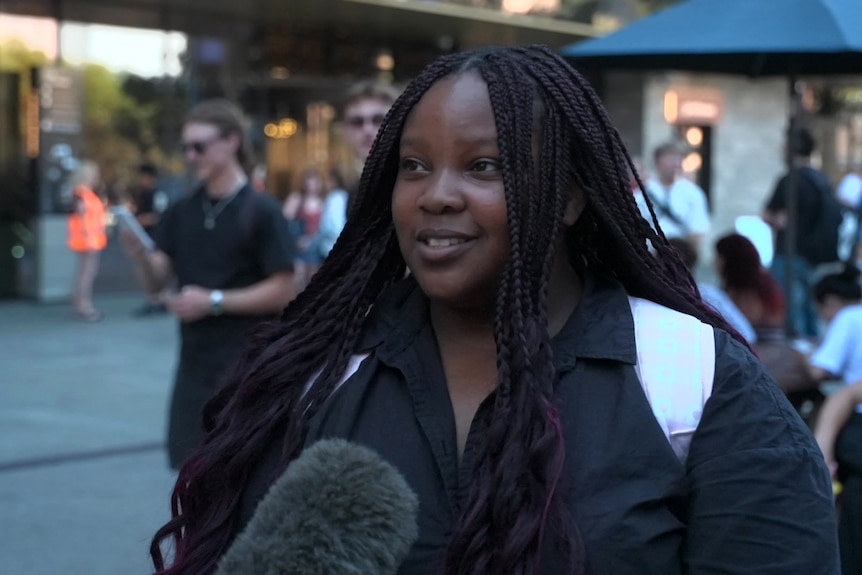 A woman with long dark hair and a jumper poses for a interview