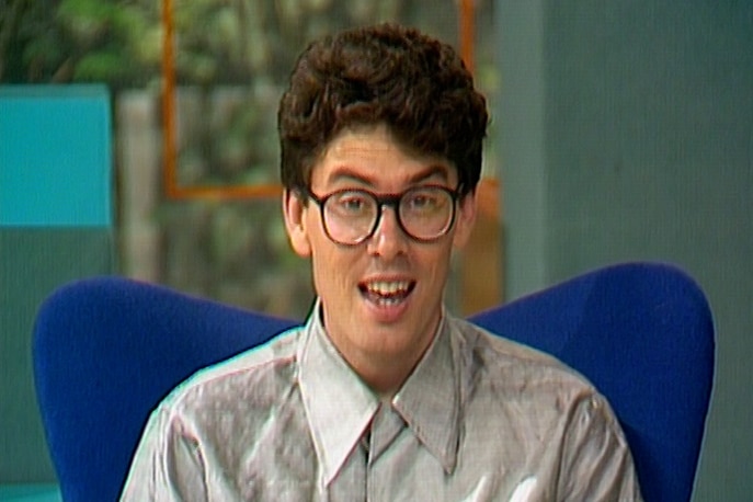 A photo of a young man with glasses talking to the camera from the late 1980s. 