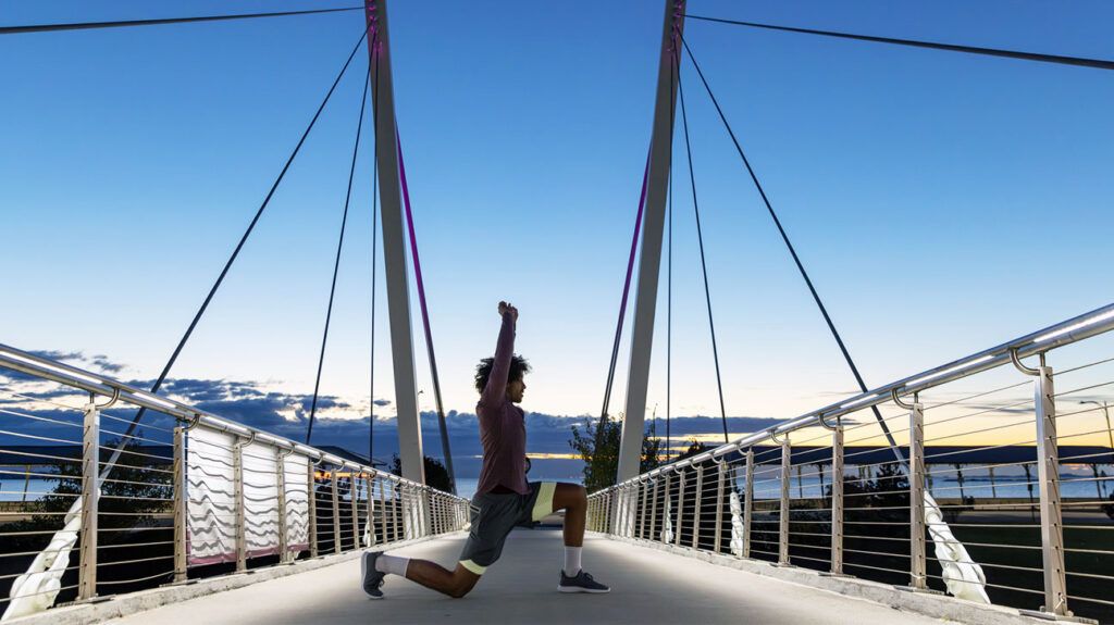 A person stretching on a bridge in the early hours of the morning