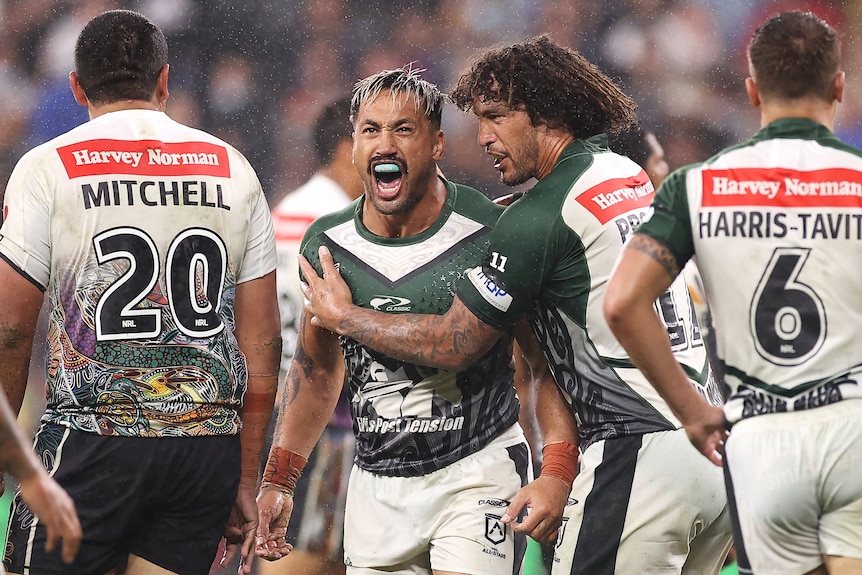 Two men congratulate each other after making a tackle in a rugby league match 