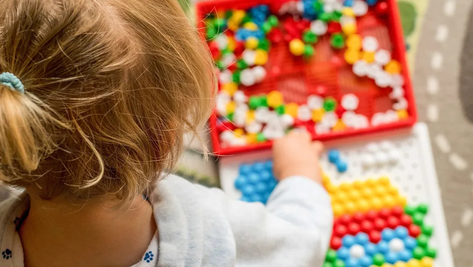 Toddler playing pegboard mosaic. Early child development. Fine motor skills. Learning and creativity