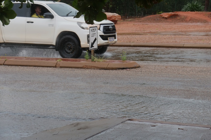 White car driving through large puddle