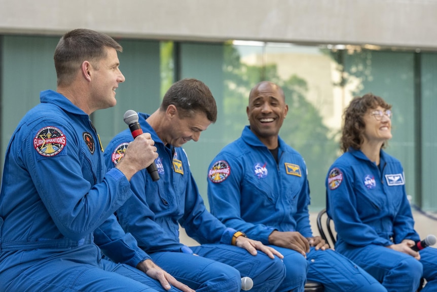 The four Artemis II astronauts sit at an event laughing.