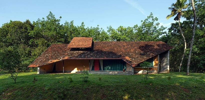a semi-circular porous brick house stands amid rubber plantation in india