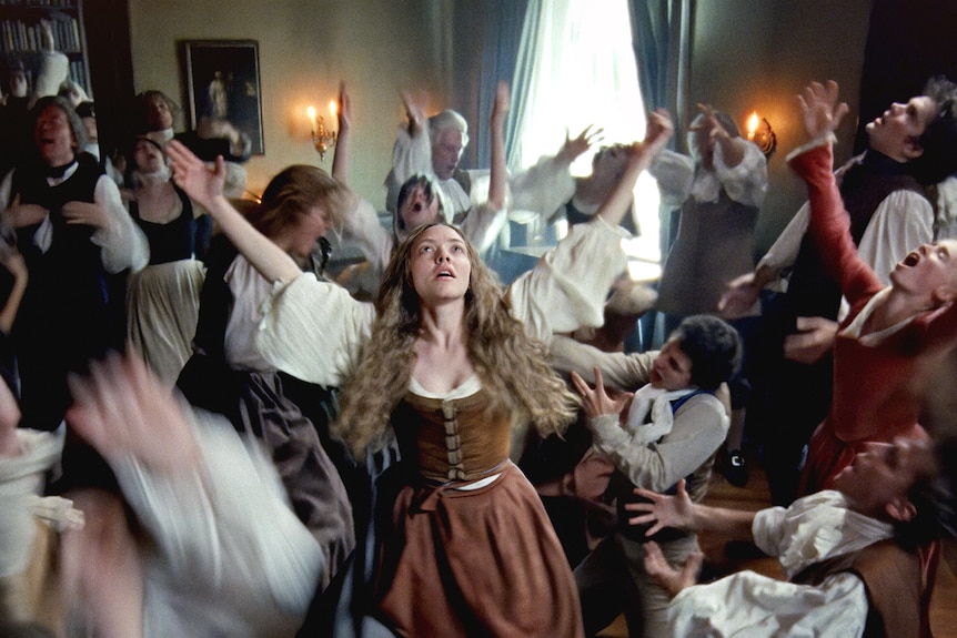 People dressed in 19th century costume dance in a room
