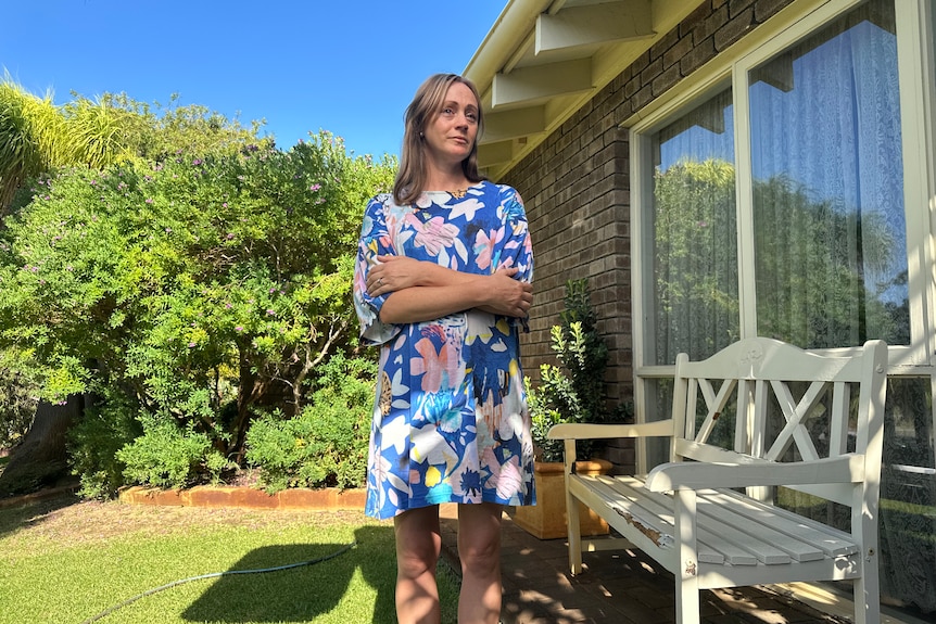 A woman sits outside holding a damaged phone and some keys. 