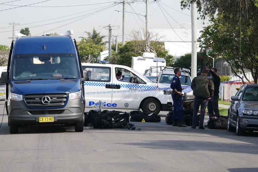 Police vehicles and officers on a suburban street.