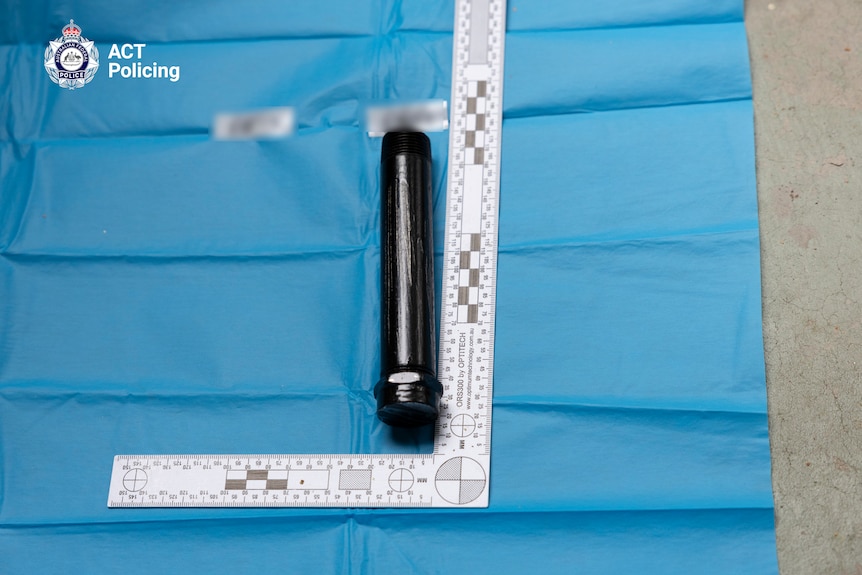 A black pipe beside a measuring tape. 