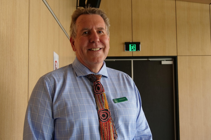 A man with a tie and shirt smiling.
