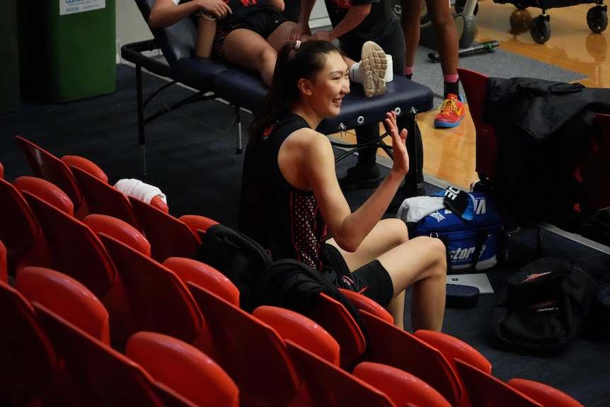 Han Xu sits courtside and waves to fans. 