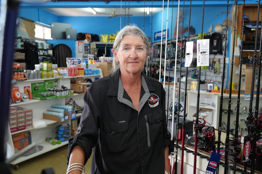 A woman stands amongst fishing rods