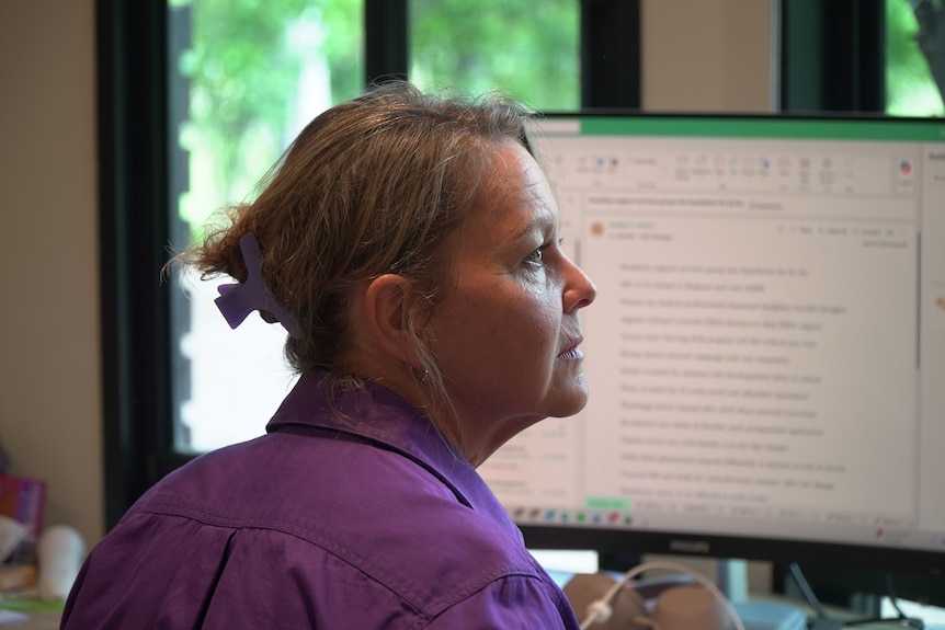 A woman with a serious expression sits in front of the office with a serious expression.