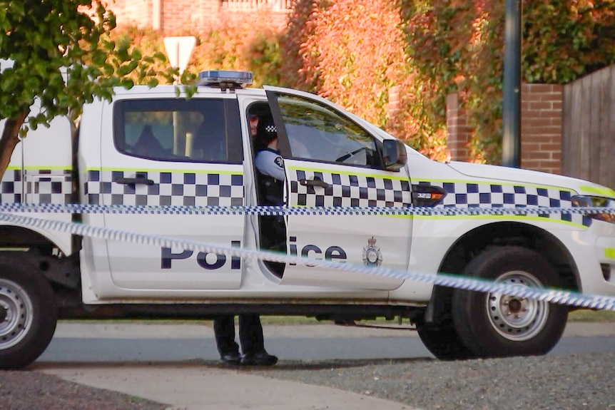 A police car behind police tape. 