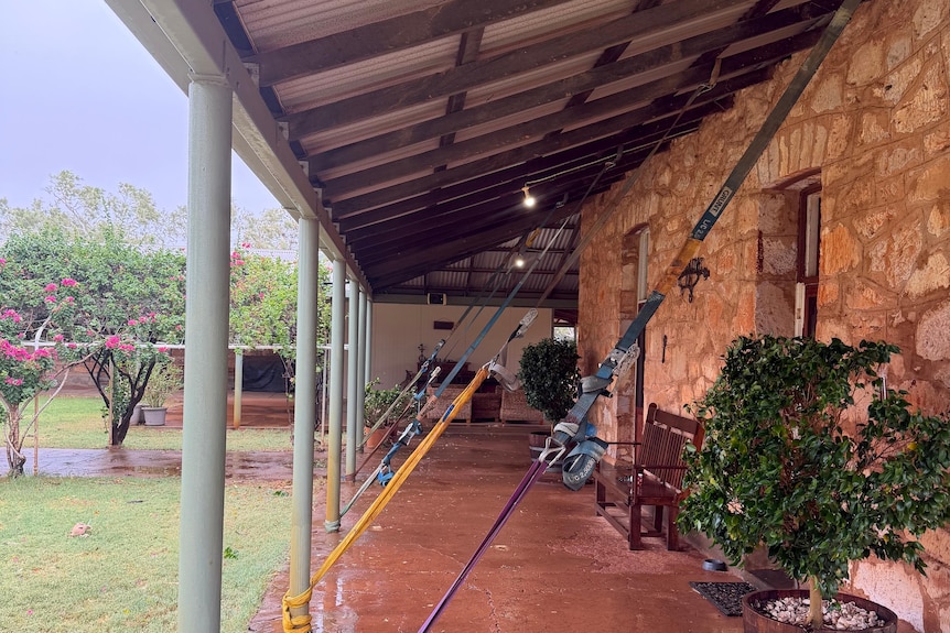 Brick house on right with straps attached to roof and poles