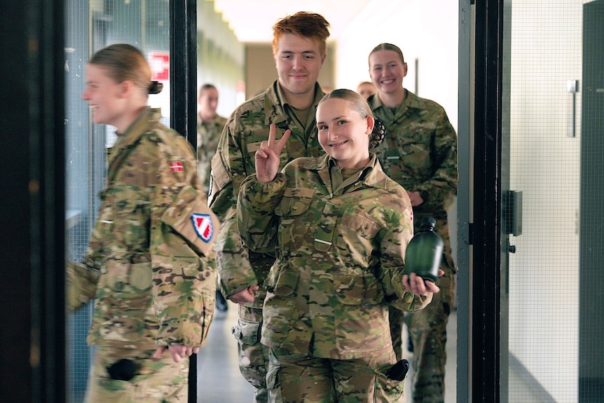 A young woman gives a peace sign.