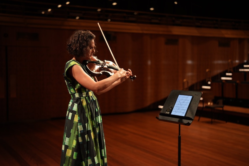 Stefanie Farrands in a green dress playing her viola.
