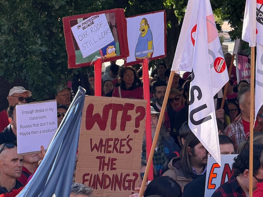 Dozens of union members with matching t-shirts and placards at a rally.