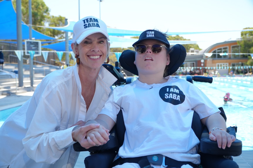 A mother and daughter are pictured in front of a swimming pool wearing a 'Team Saba' cap