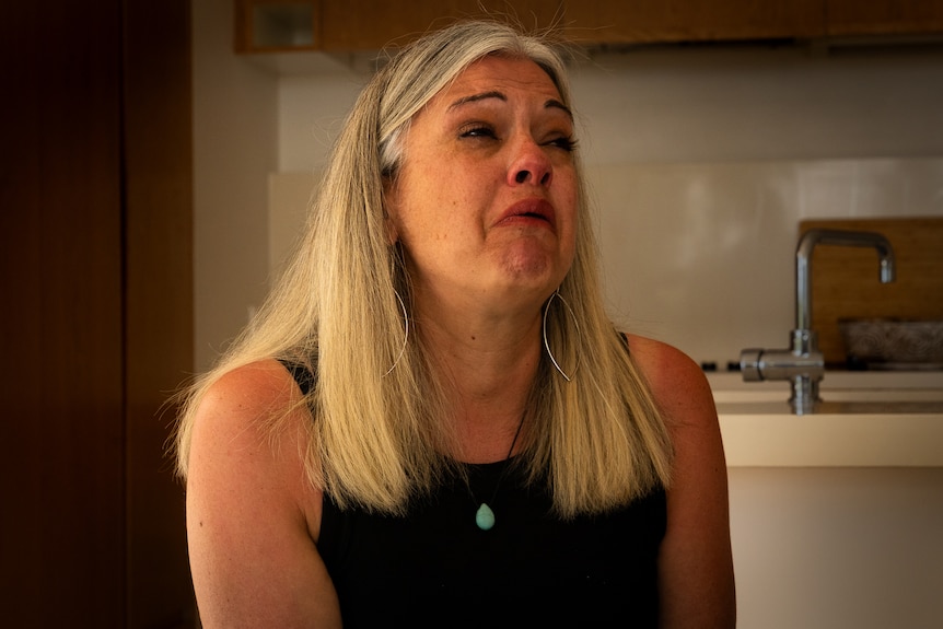 Woman with silver hair crying.