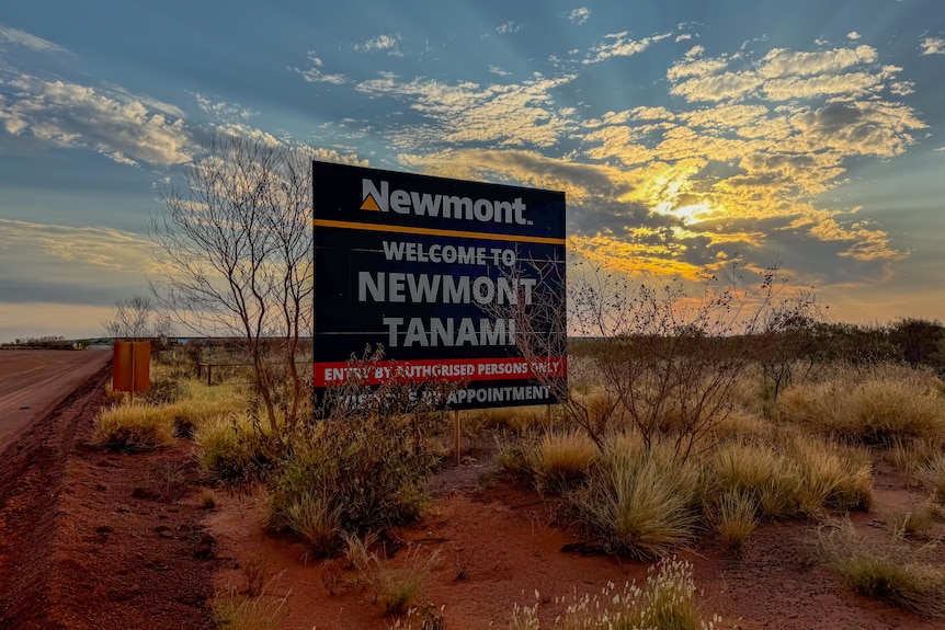 A navy Newmont Tanami welcome sign at sunset in the desert.